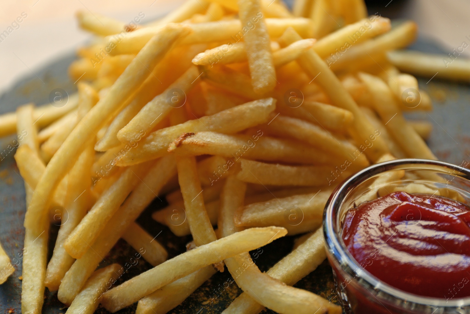 Photo of Tasty French fries with red sauce served on table in cafe, closeup