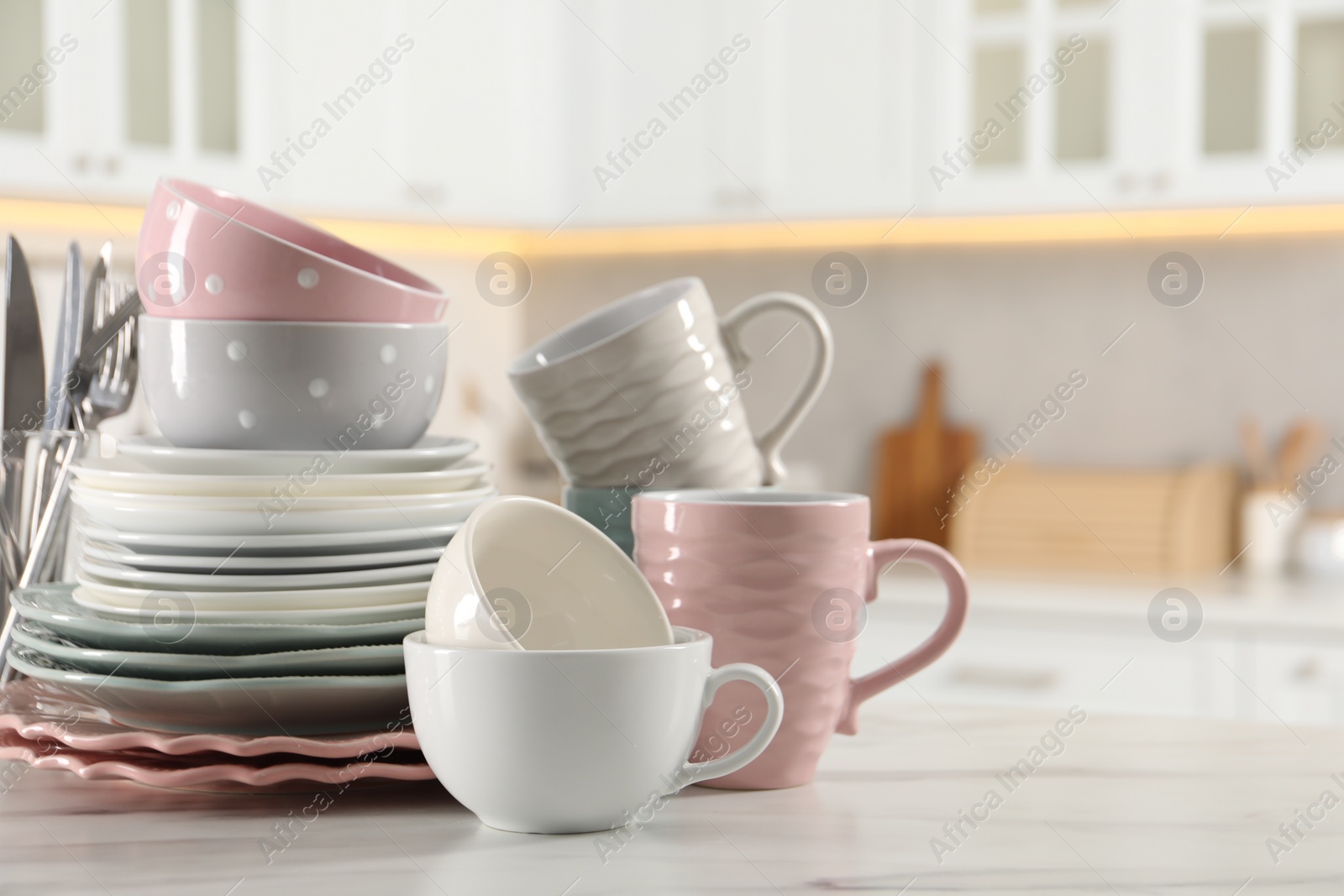 Photo of Many different clean dishware and cups on white marble table in kitchen. Space for text