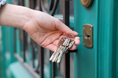 Woman opening door with key outdoors, closeup