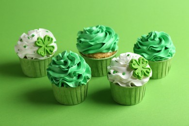 St. Patrick's day party. Tasty festively decorated cupcakes on green background