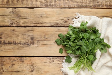 Photo of Bunch of fresh aromatic cilantro on wooden table, top view. Space for text