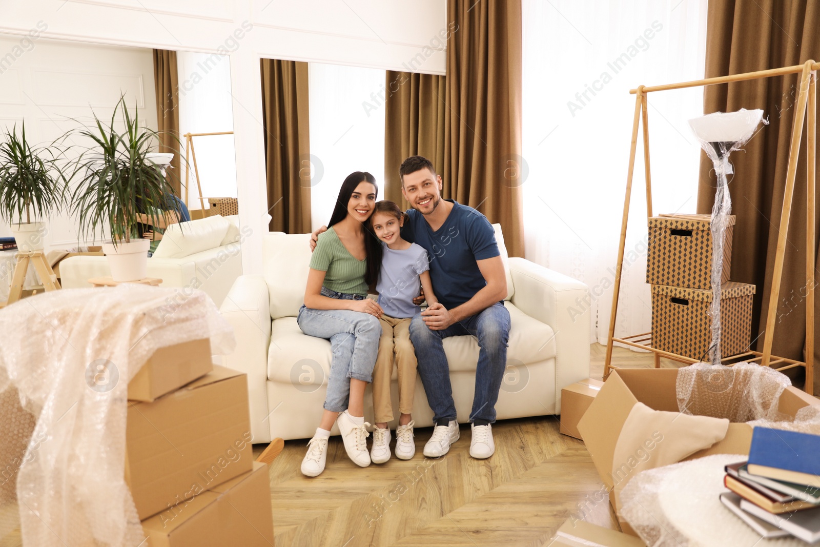 Photo of Happy family sitting on sofa in new house. Moving day
