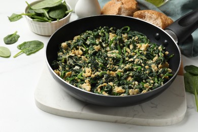 Photo of Tasty spinach dip with eggs in dish served on white table, closeup