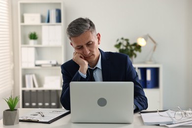 Photo of Sleepy man at table with laptop in office