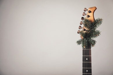 Photo of Guitar with fir tree branch on light background, space for text. Christmas music