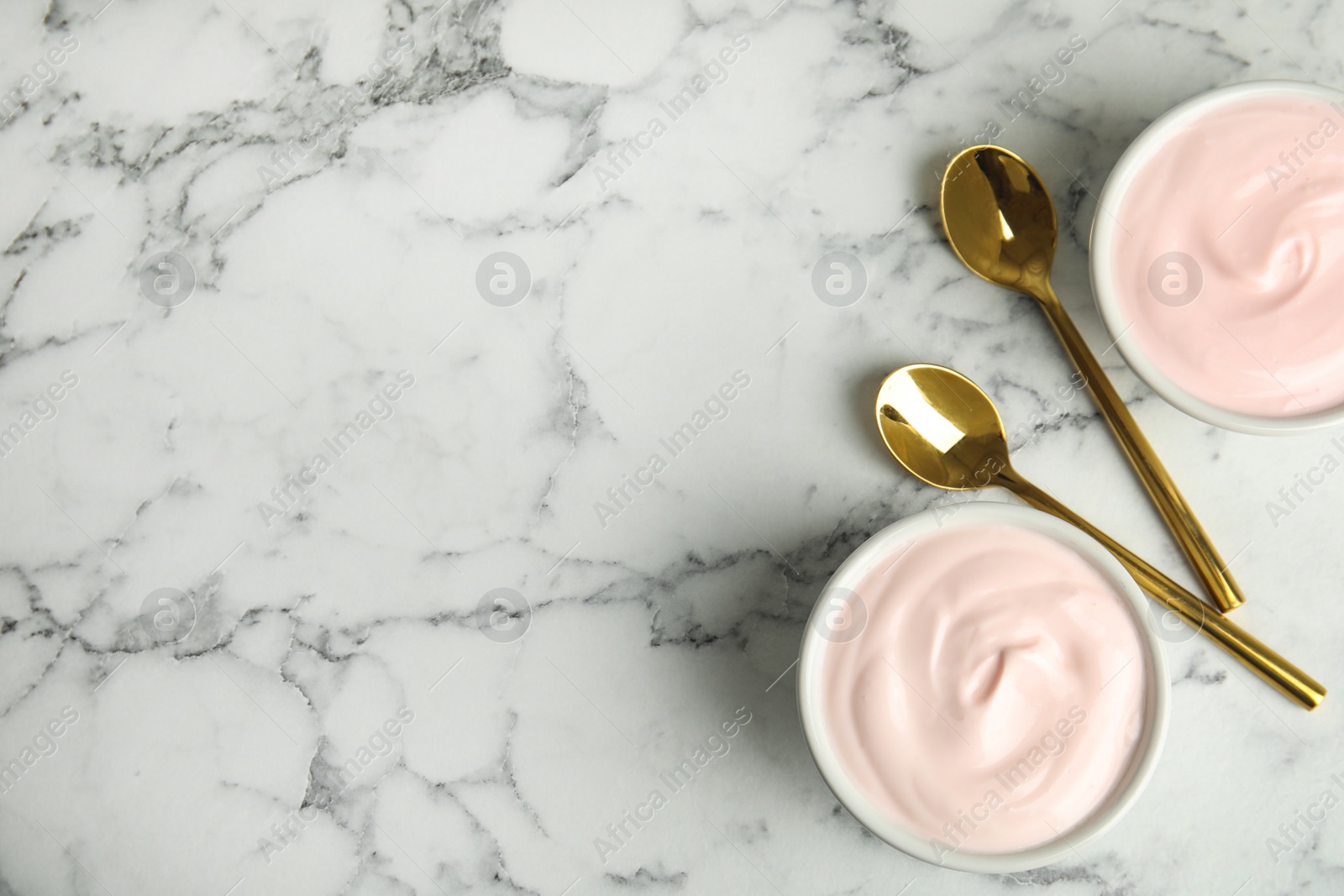 Photo of Tasty organic yogurt on white marble table, flat lay. Space for text