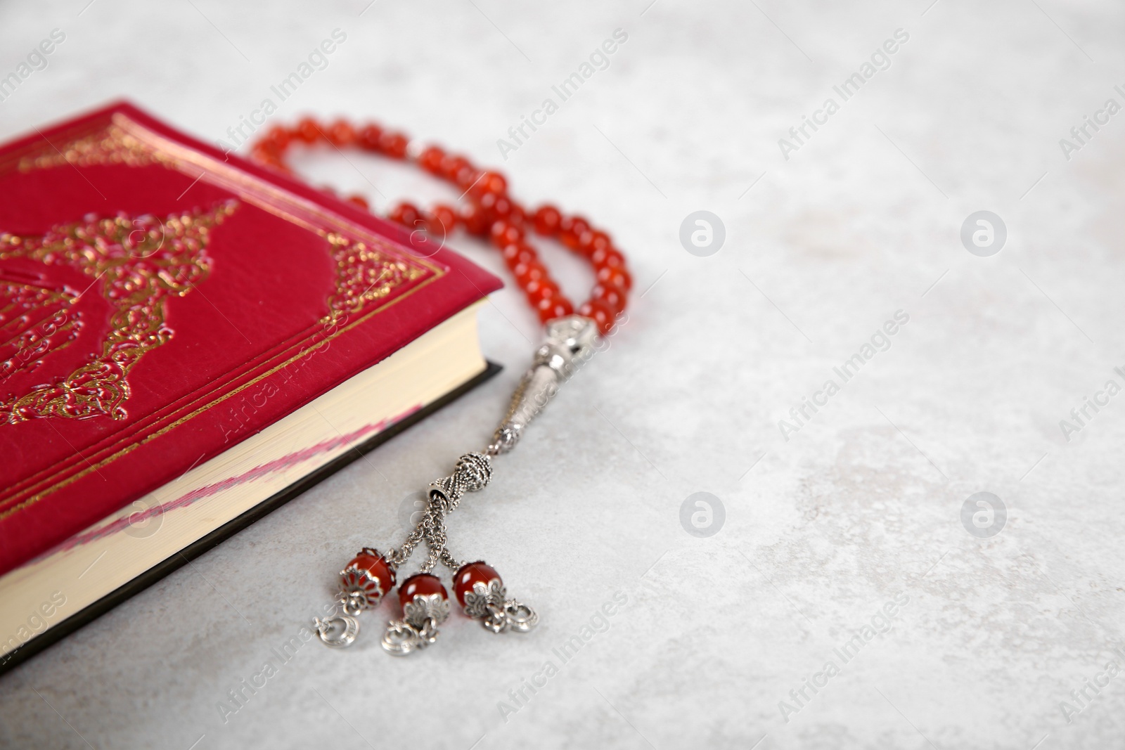 Photo of Muslim prayer beads, Quran and space for text on grey background