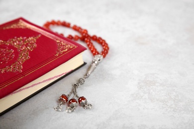 Photo of Muslim prayer beads, Quran and space for text on grey background