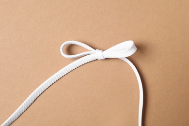Photo of White shoelace on brown background, top view