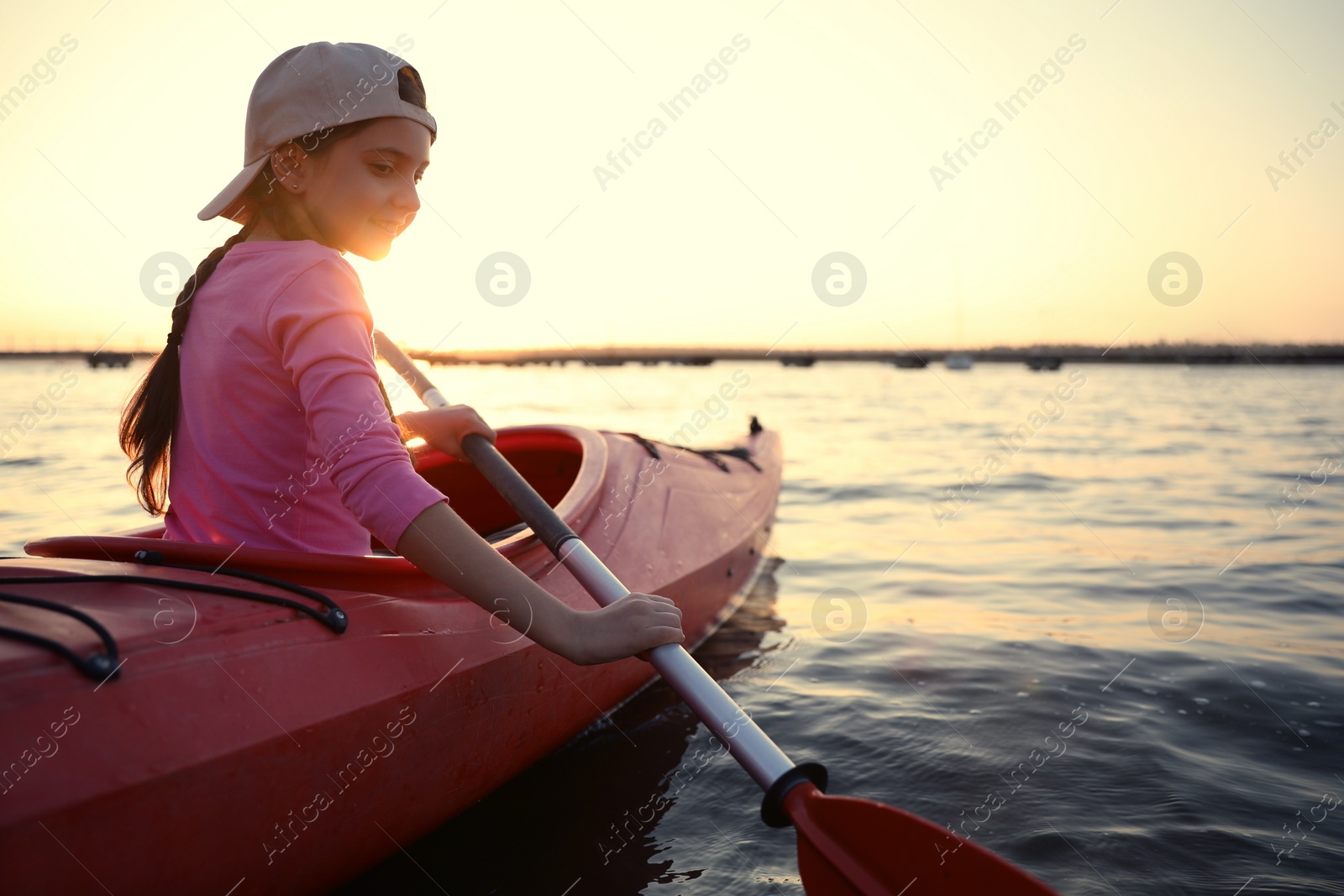 Photo of Happy girl kayaking on river at sunset. Summer camp activity