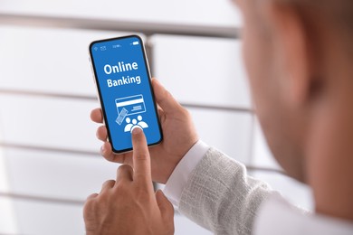 Image of Man using online banking application on smartphone indoors, closeup