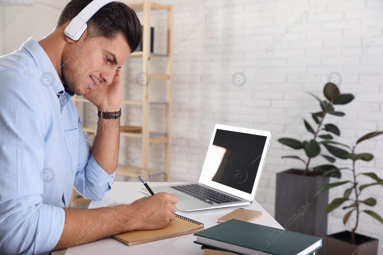 Photo of Man listening to audiobook at table with laptop