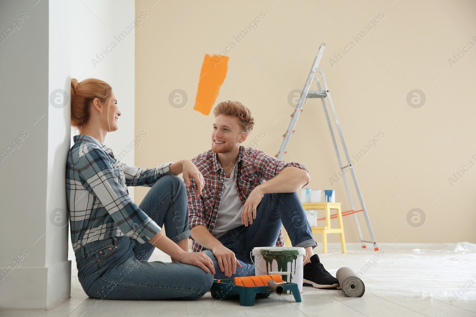 Photo of Happy couple with paint planning home repair indoors
