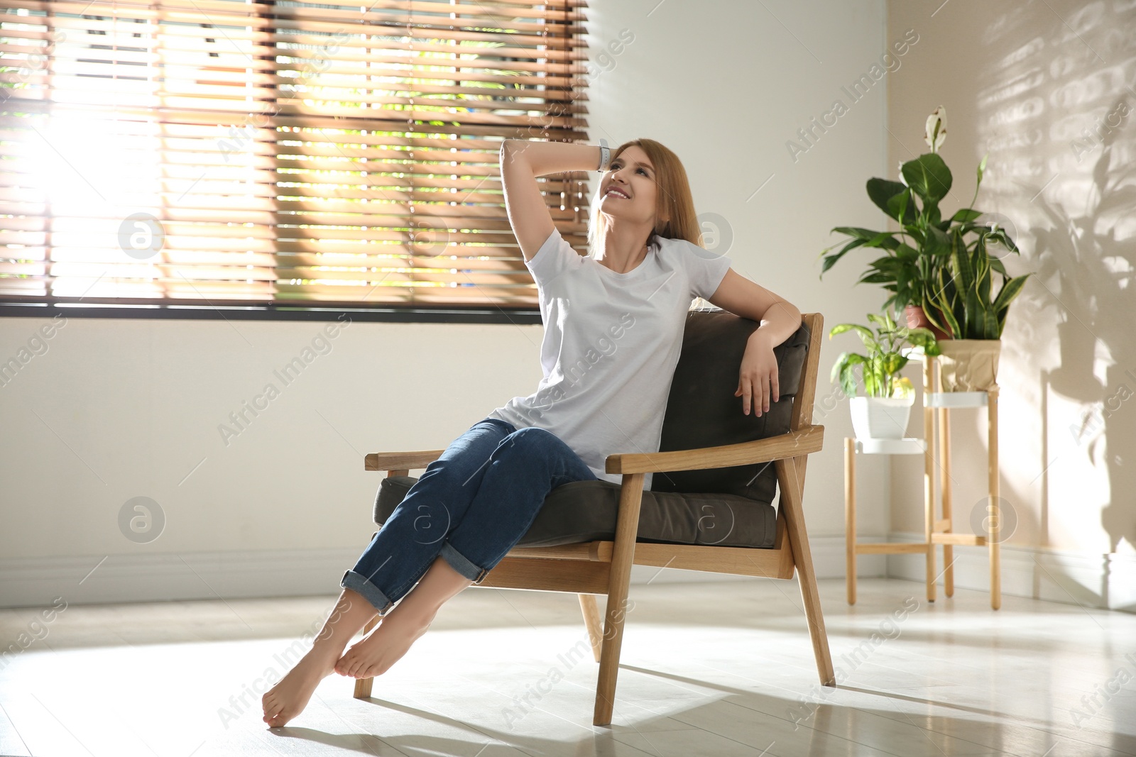 Photo of Young woman relaxing in armchair near window at home. Space for text