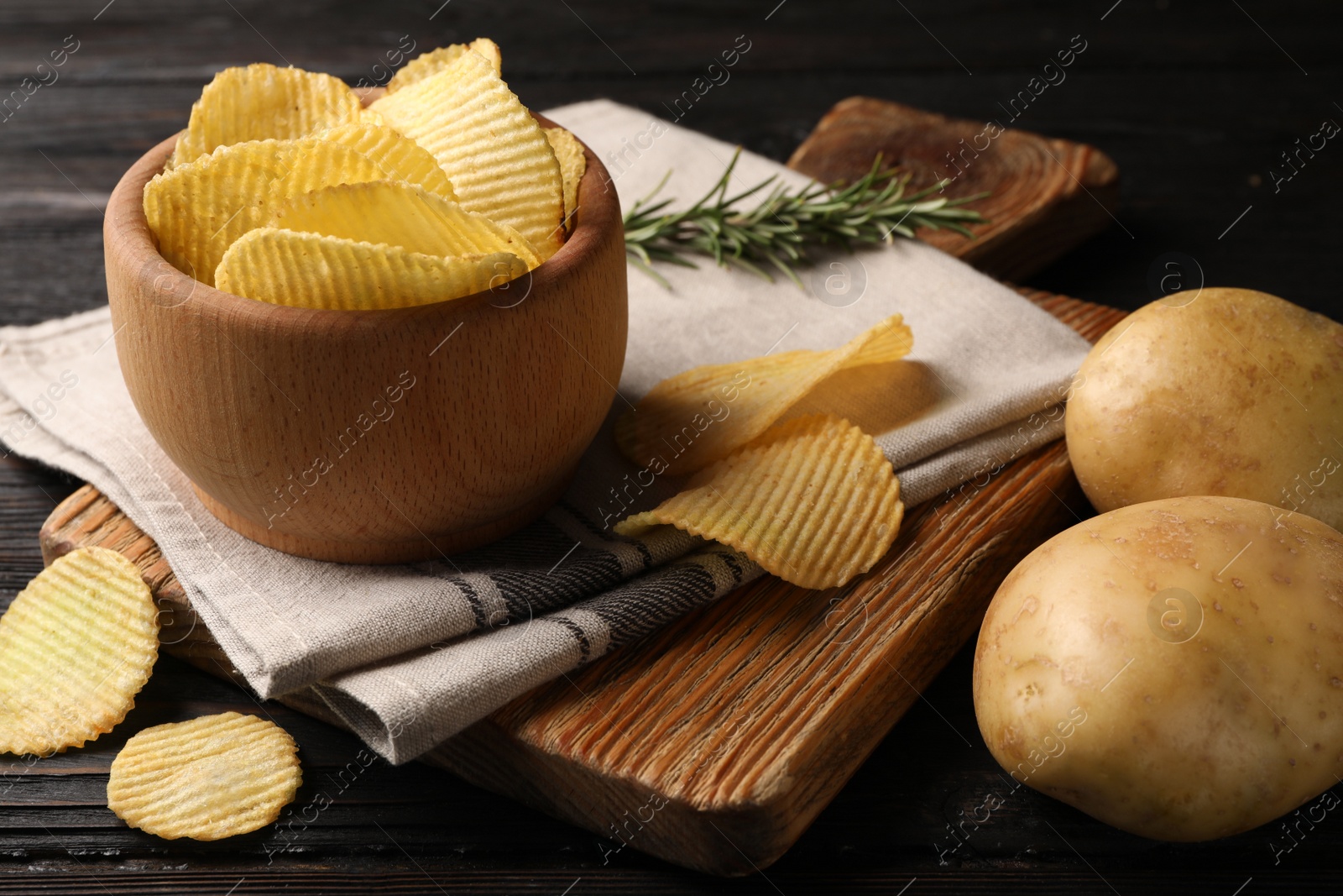 Photo of Bowl of crispy potato chips on wooden table