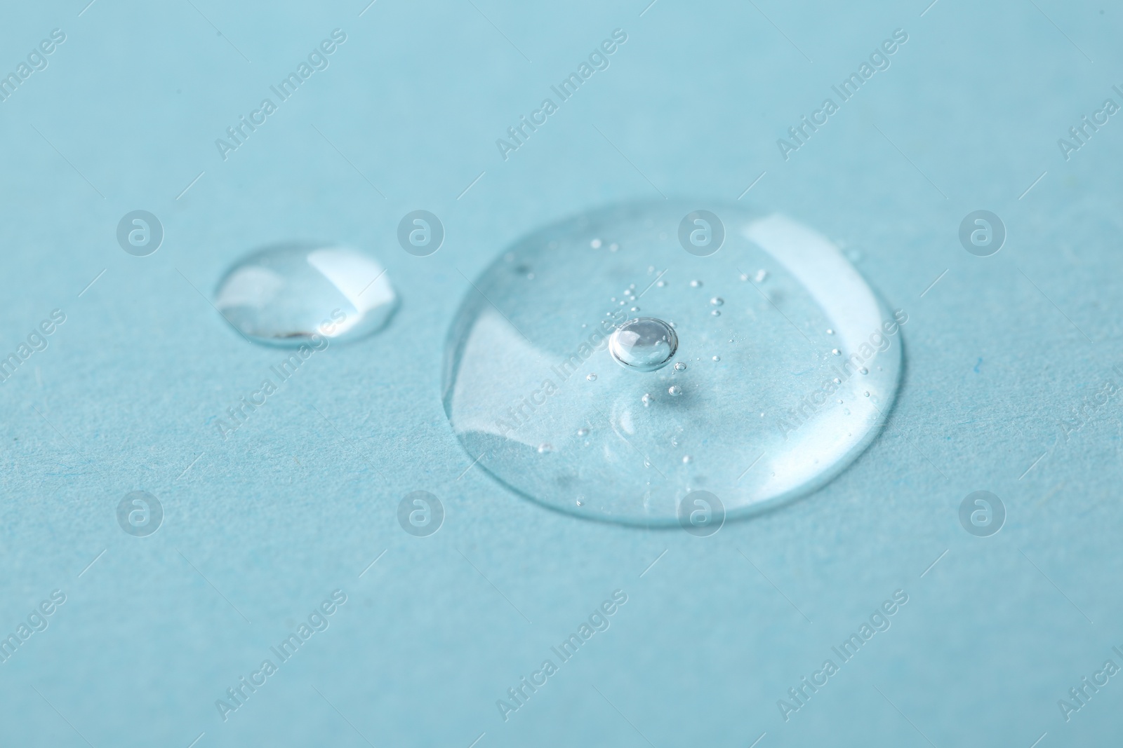 Photo of Samples of cosmetic serum on light blue background, closeup