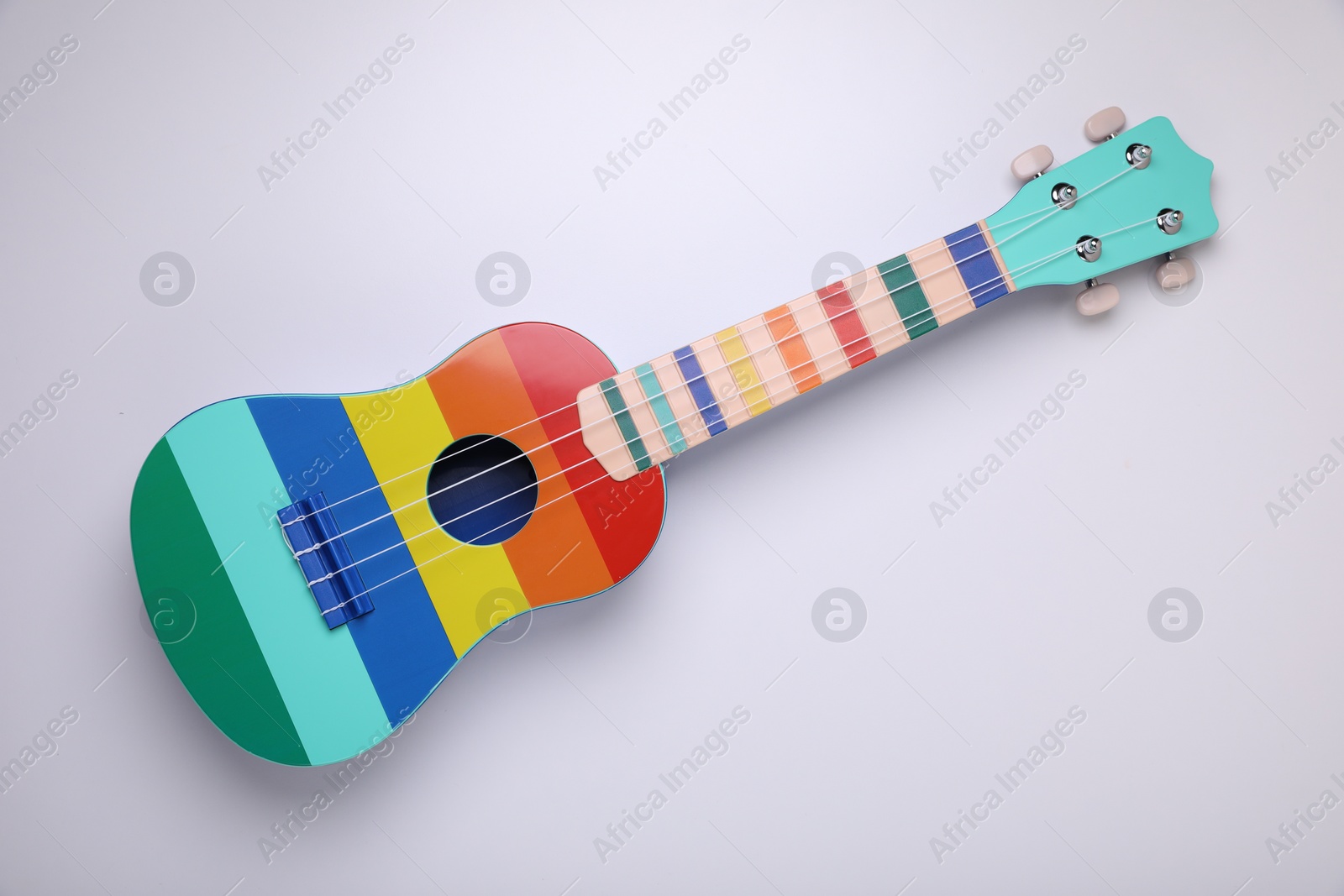 Photo of Colorful ukulele on white background, top view. String musical instrument