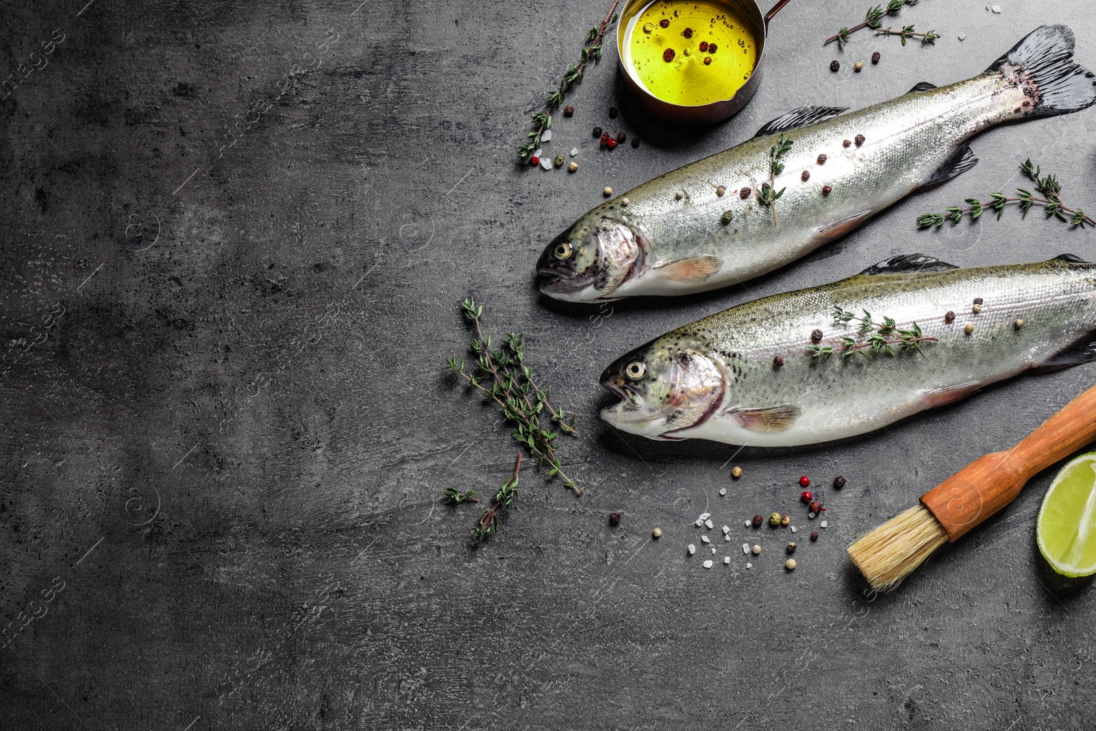 Photo of Flat lay composition with raw cutthroat trout fish on grey table, space for text