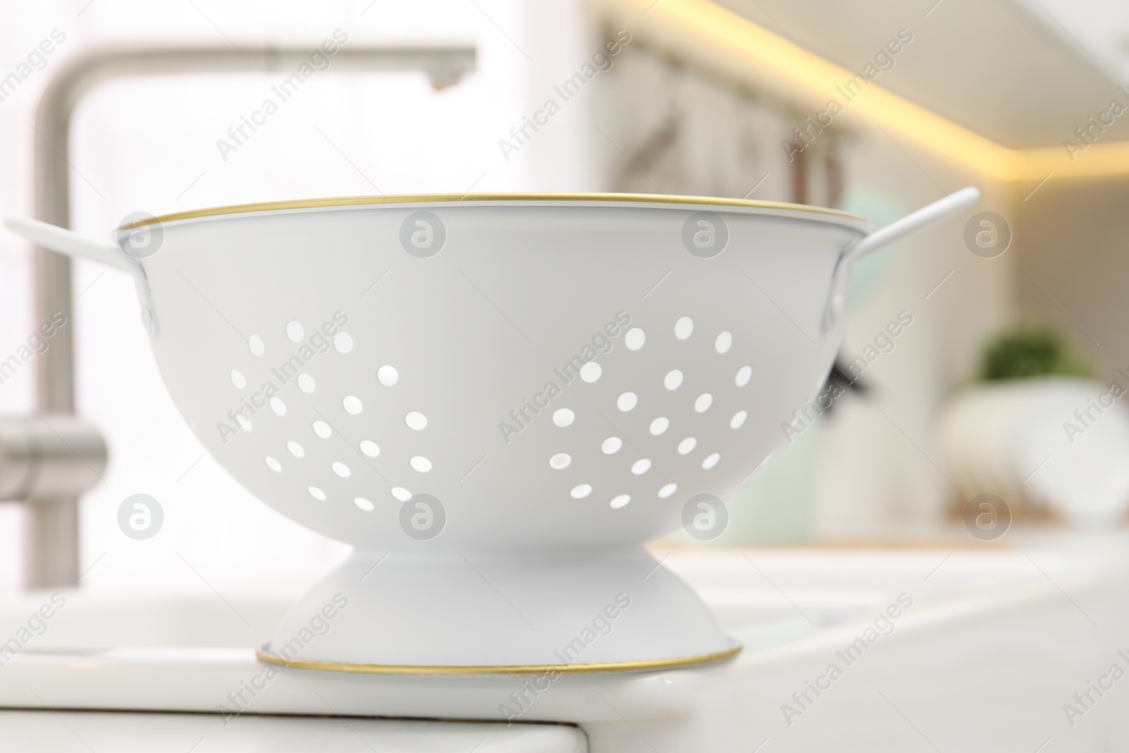 Photo of White clean colander on countertop in kitchen, closeup