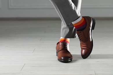 Man wearing stylish shoes and colorful socks indoors, closeup. Space for text