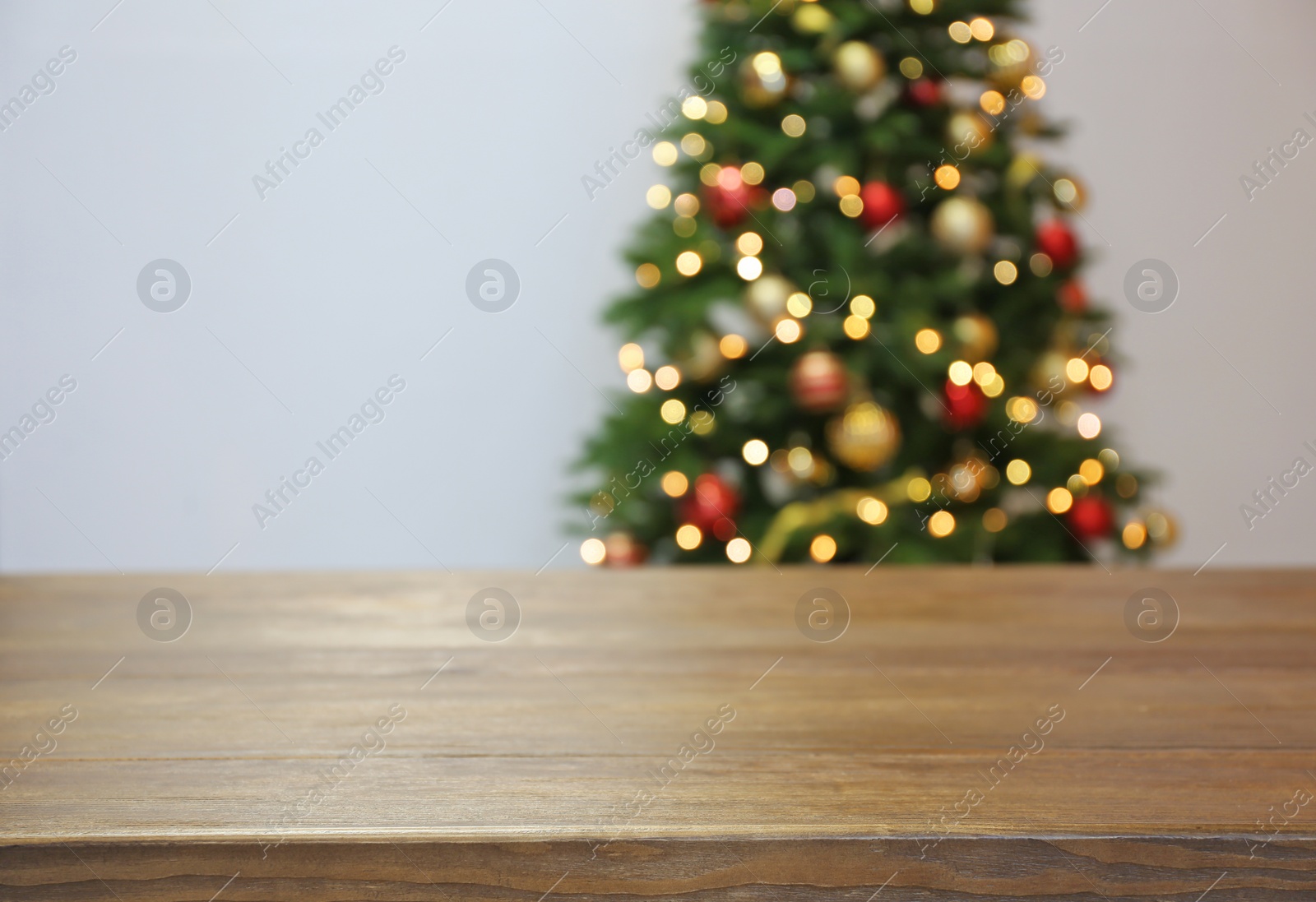 Photo of Wooden table and blurred Christmas tree with fairy lights on background