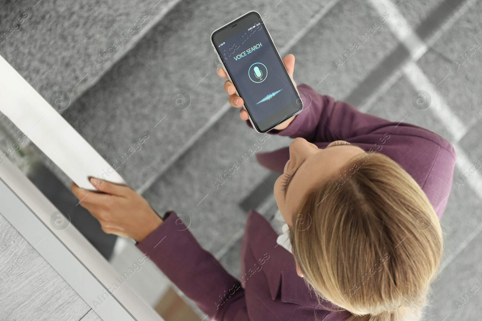 Photo of Young woman using voice search on smartphone indoors, above view