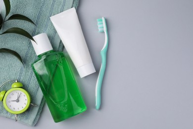 Photo of Flat lay composition with fresh mouthwash in bottle and other oral care products on grey background. Space for text