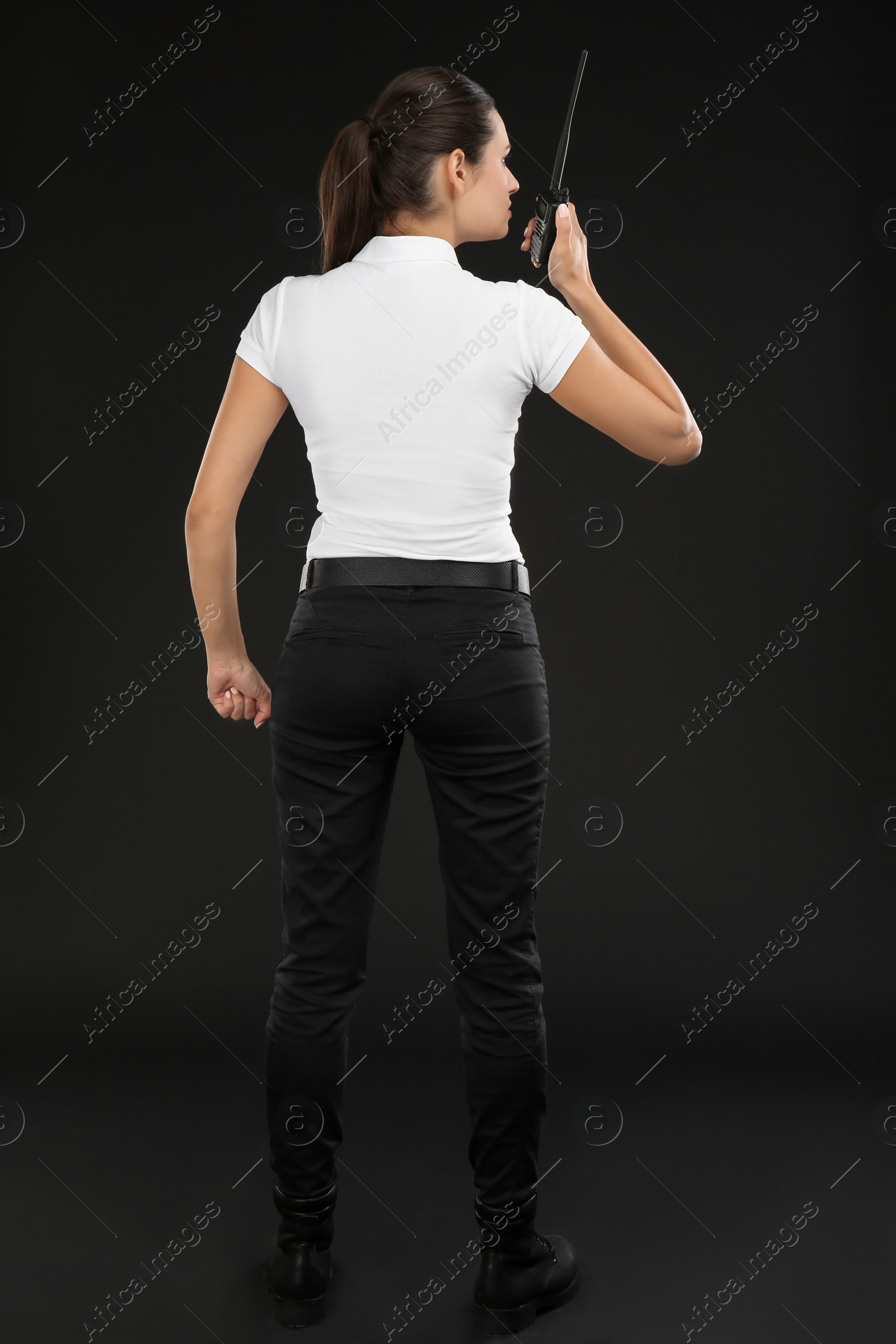 Photo of Female security guard using portable radio transmitter on dark background