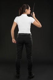 Photo of Female security guard using portable radio transmitter on dark background