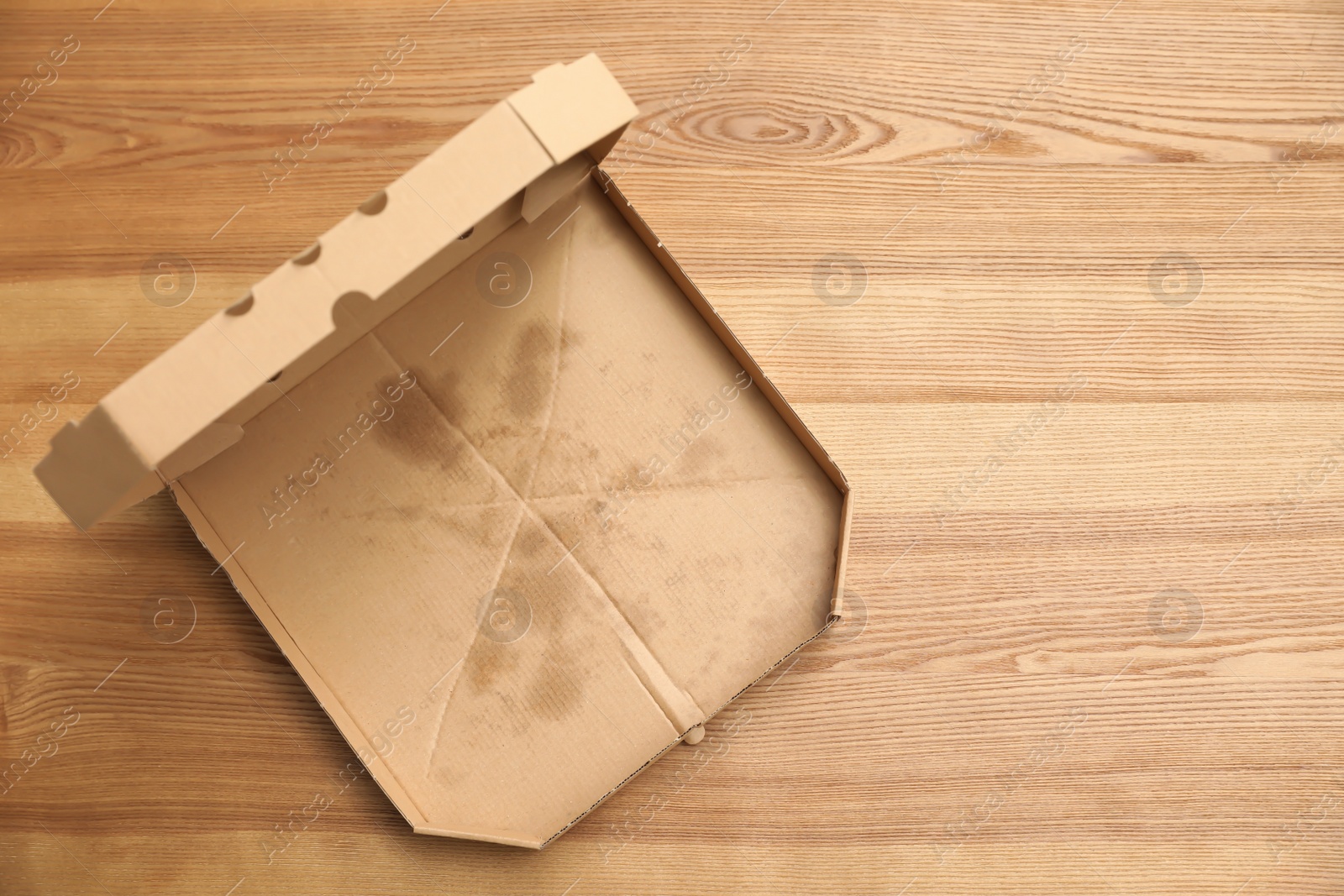 Photo of Cardboard pizza box on wooden background, top view with space for text