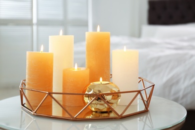 Golden tray with burning candles on table in bedroom