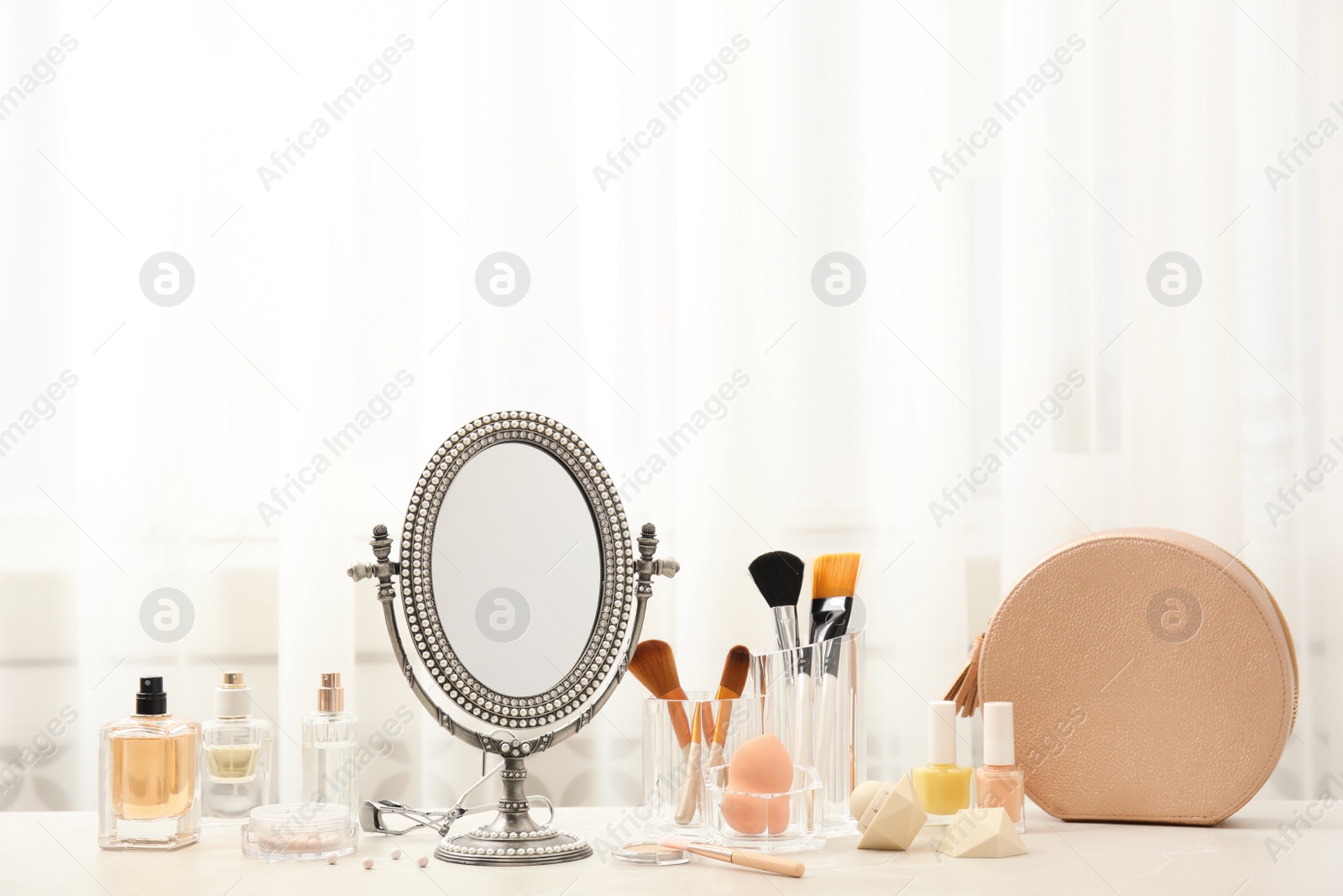 Photo of Mirror in antique frame and different cosmetics on dressing table, space for text. Beauty blogger