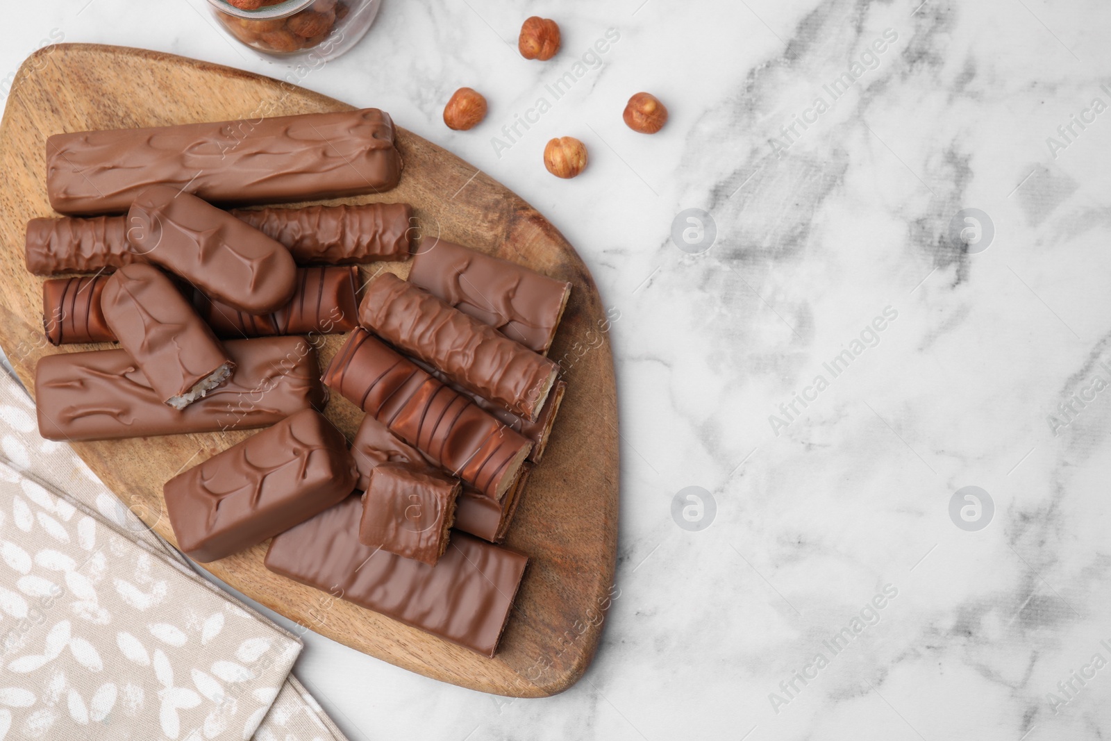 Photo of Different tasty chocolate bars and hazelnuts on white marble table, flat lay. Space for text