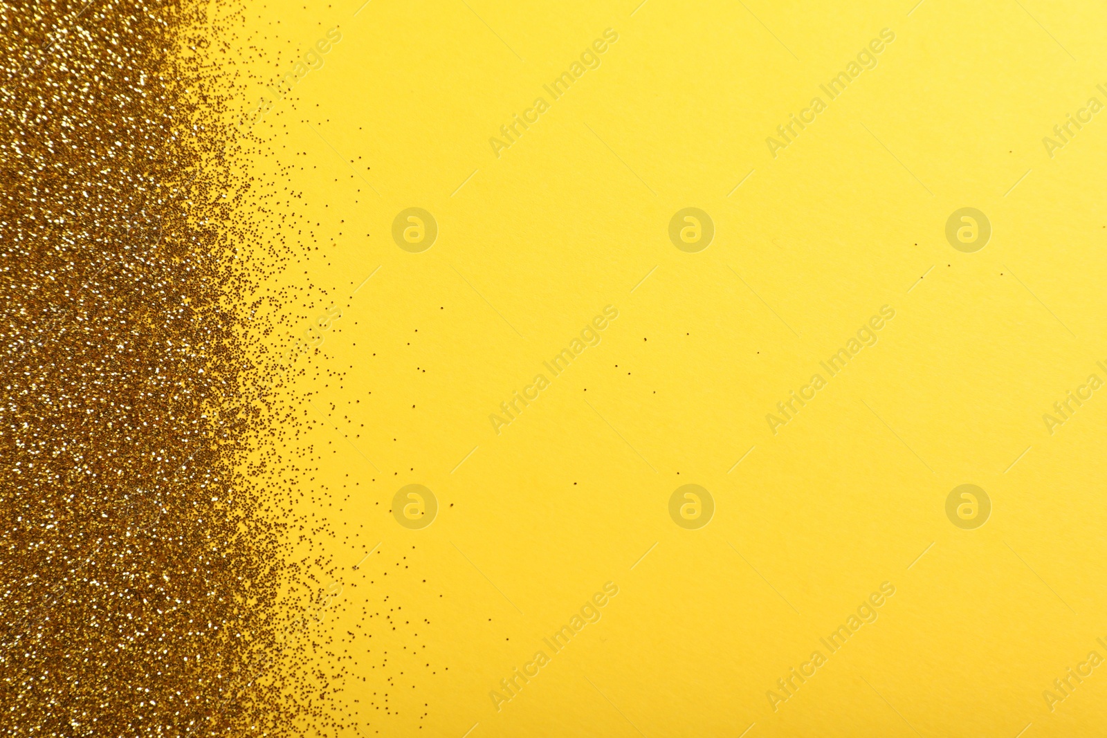 Photo of Shiny golden glitter on yellow background, top view. Space for text