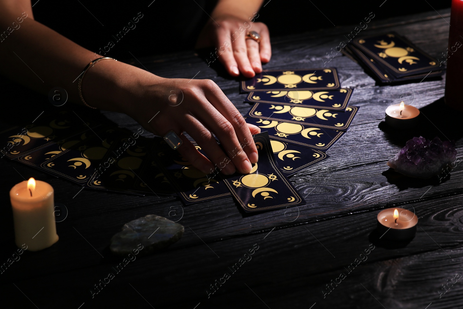 Photo of Soothsayer predicting future with tarot cards at table in darkness, closeup