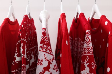 Rack with different Christmas sweaters on white background, closeup