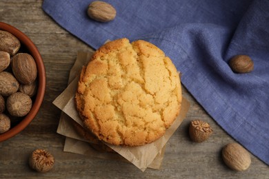 Photo of Tasty cookies and nutmeg seeds on wooden table, flat lay