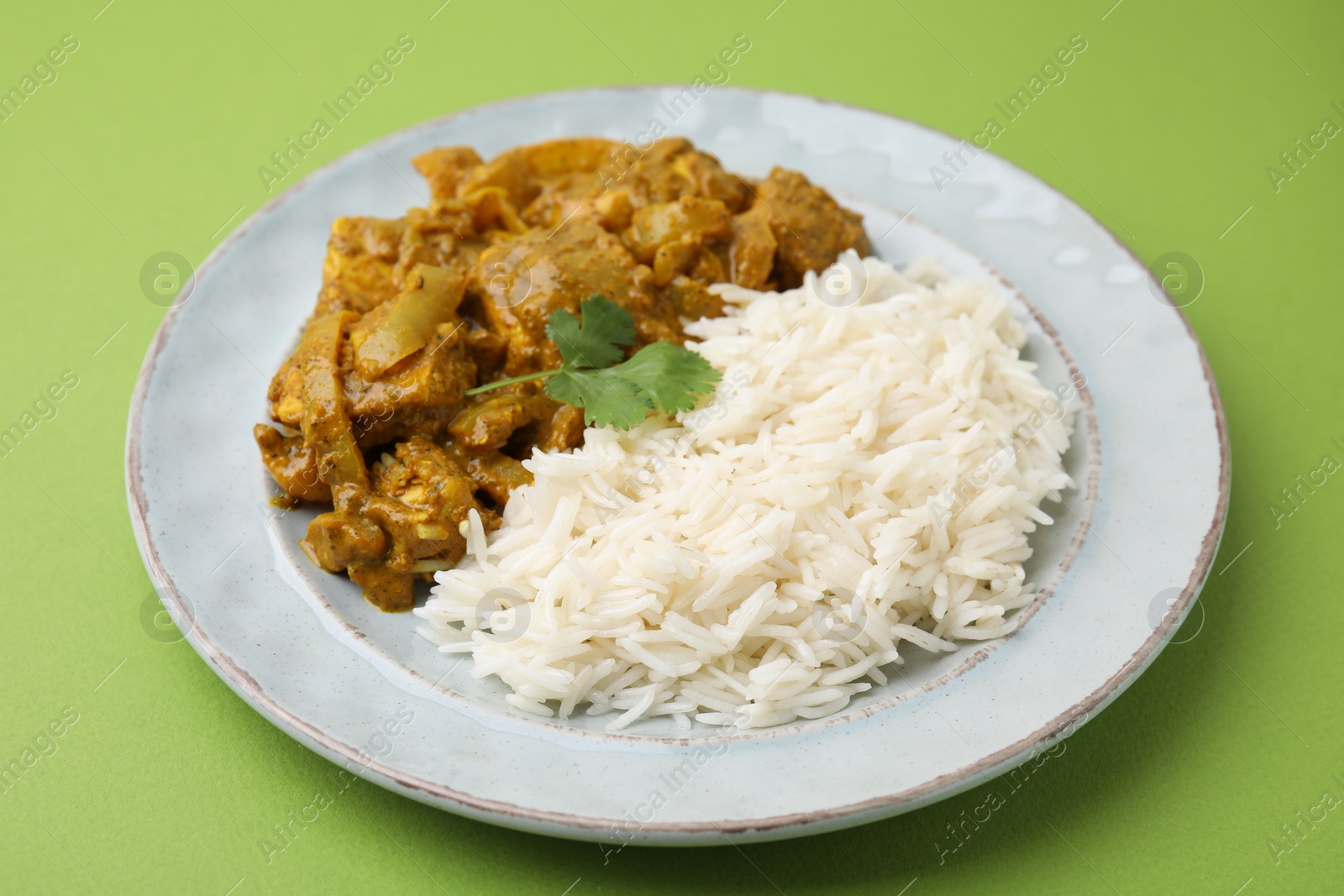 Photo of Delicious chicken curry with rice on green background, closeup