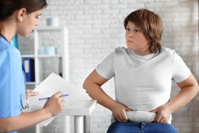 Photo of Overweight boy consulting with doctor in clinic