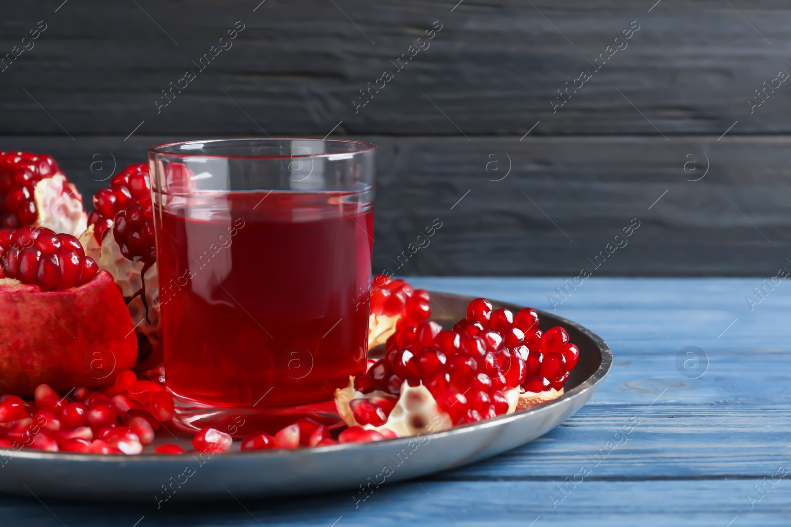 Photo of Tray with glass of pomegranate juice and fresh fruits on table against wooden background, space for text