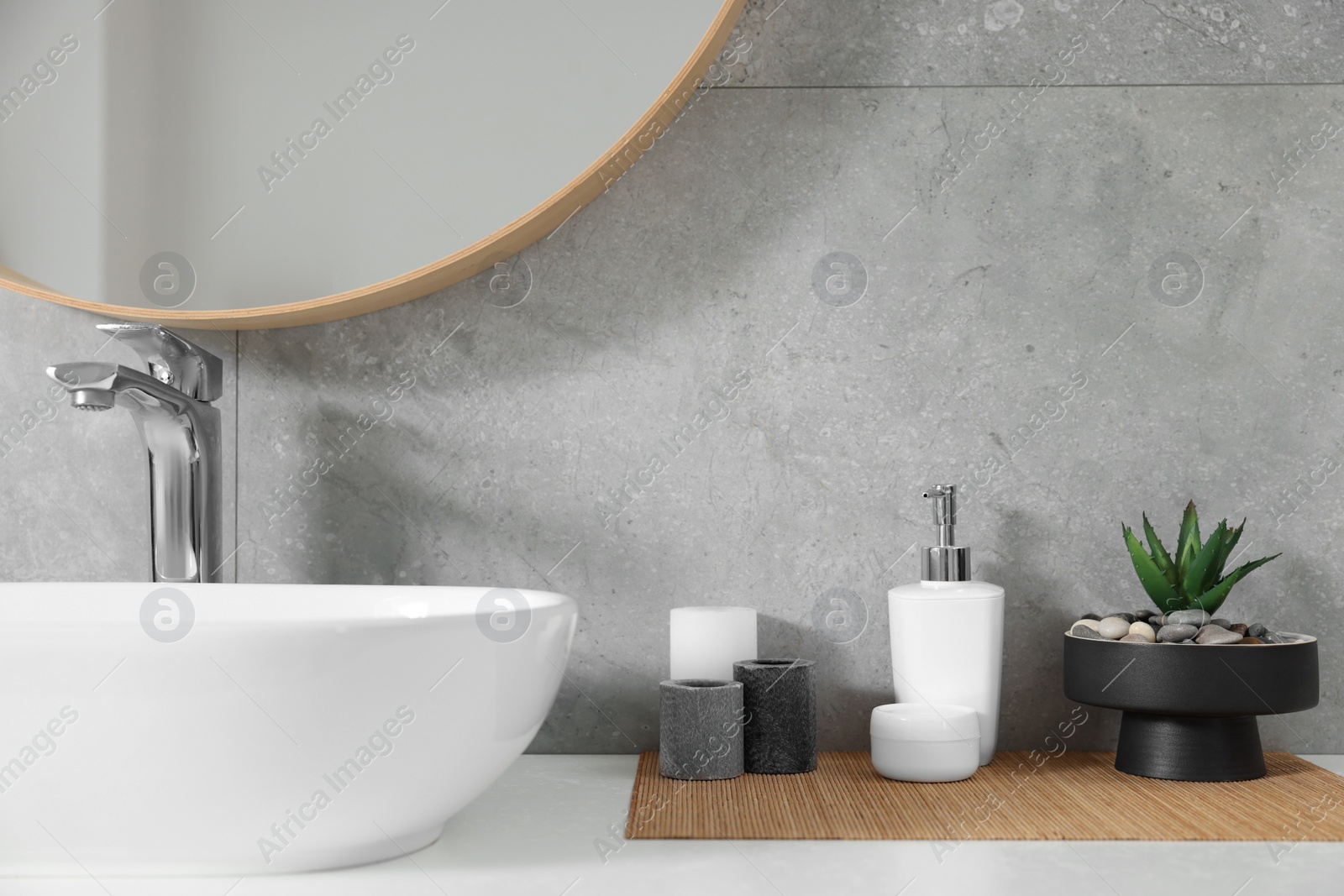 Photo of Potted artificial plant, liquid soap and candles near sink on bathroom vanity