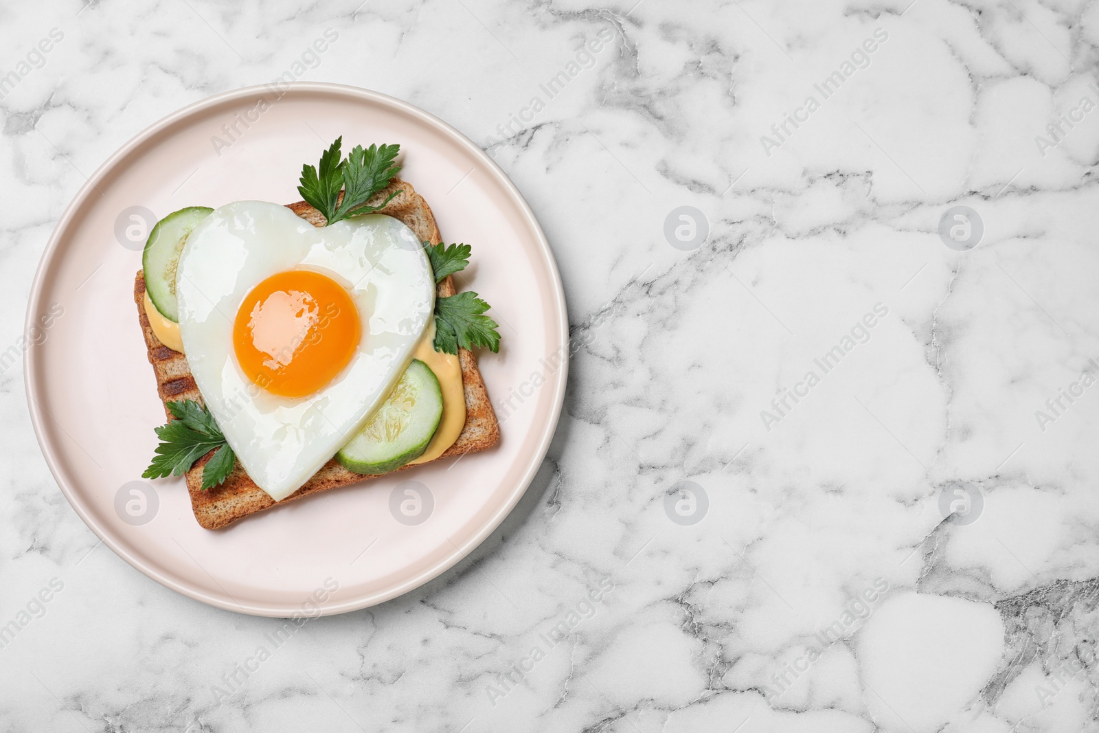 Photo of Plate of tasty sandwich with heart shaped fried egg on white marble table, top view. Space for text