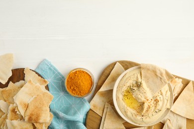 Delicious hummus with pita chips on white wooden table, flat lay. Space for text