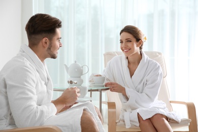 Photo of Romantic young couple with tea in spa salon