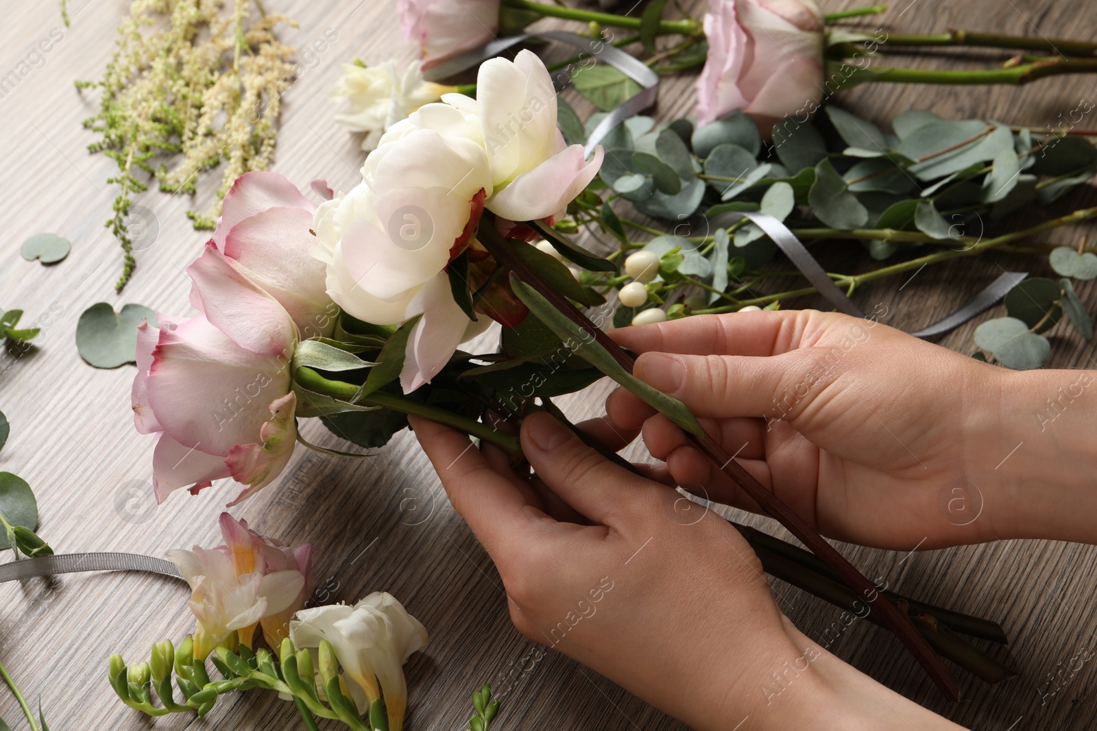 Photo of Florist creating beautiful bouquet at wooden table, closeup