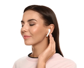 Happy young woman listening to music through wireless earphones on white background