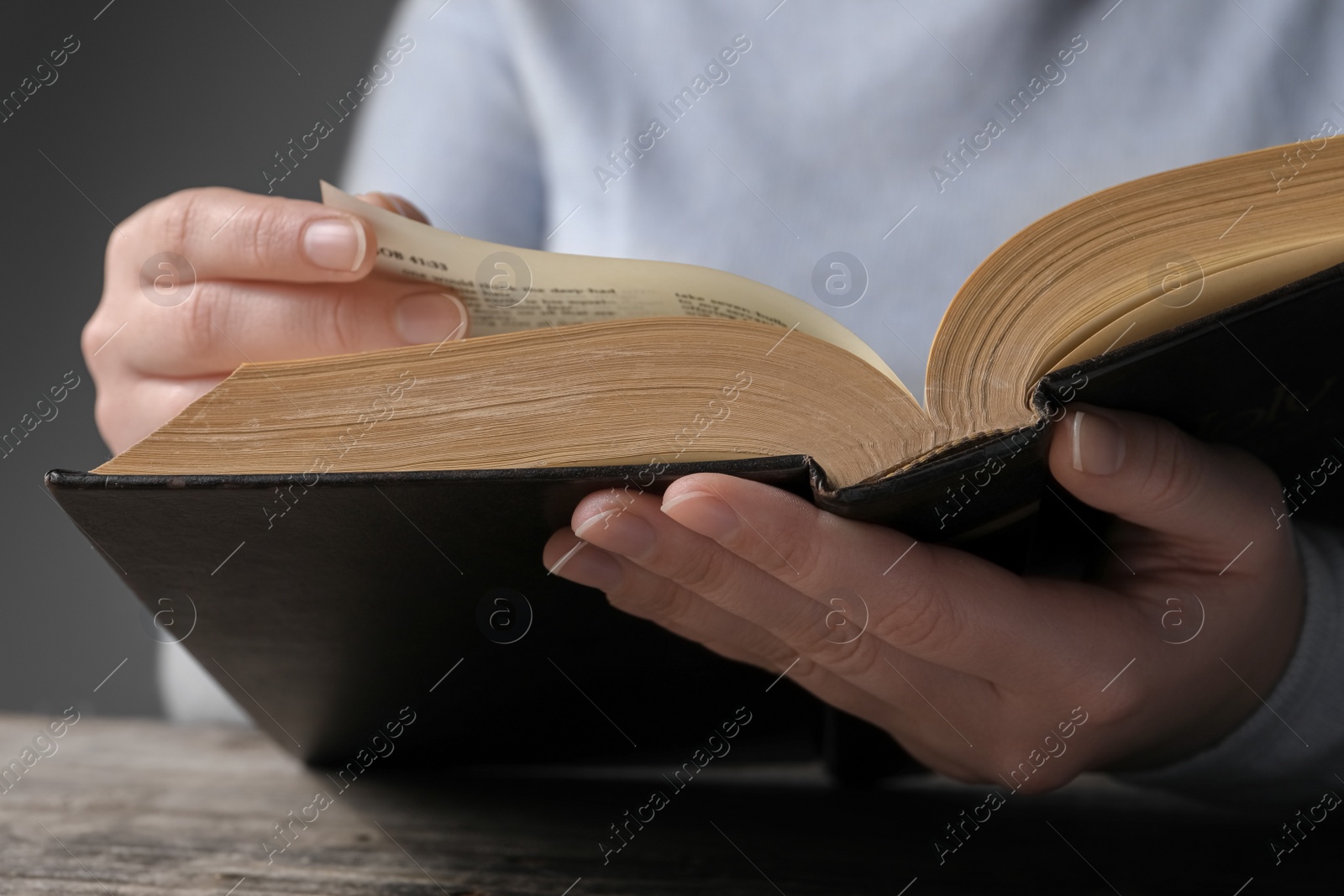 Photo of Woman reading Bible at wooden table, closeup