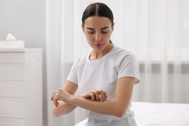 Woman with dry skin checking her arm indoors