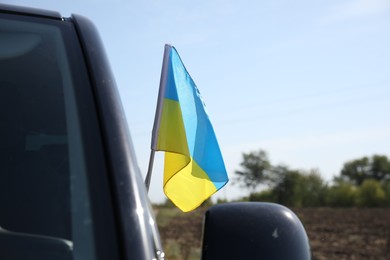 Photo of National flag of Ukraine on car window outdoors, closeup