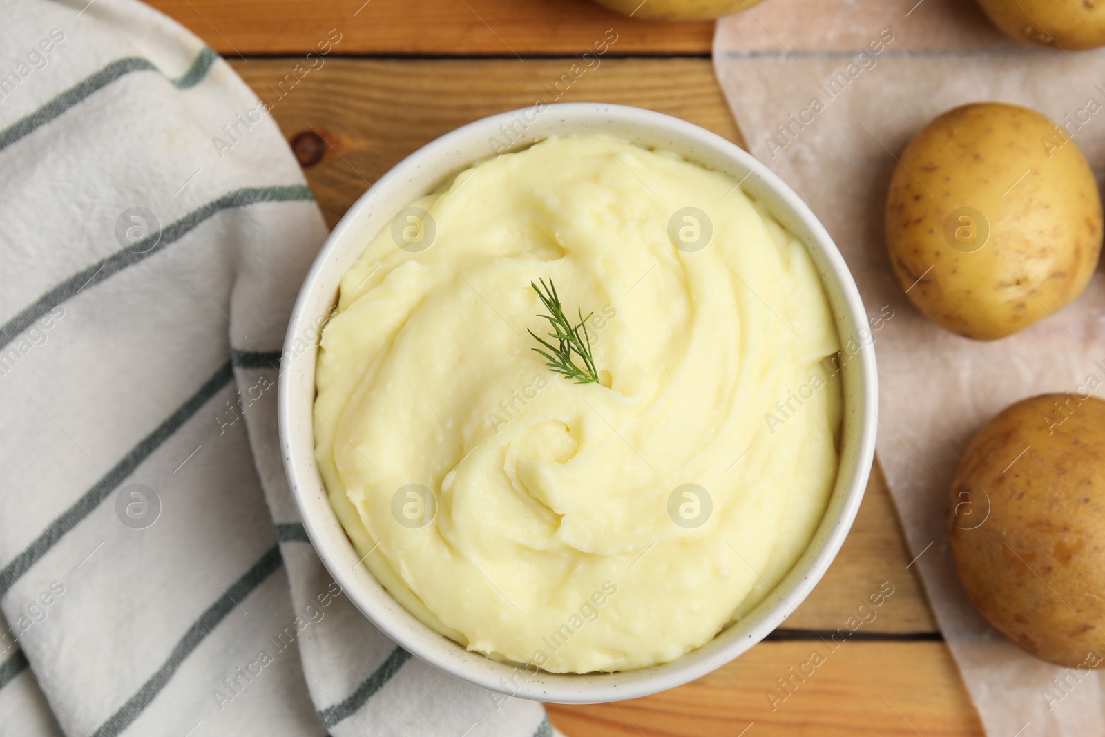 Photo of Freshly cooked homemade mashed potatoes and raw vegetables on wooden table, flat lay